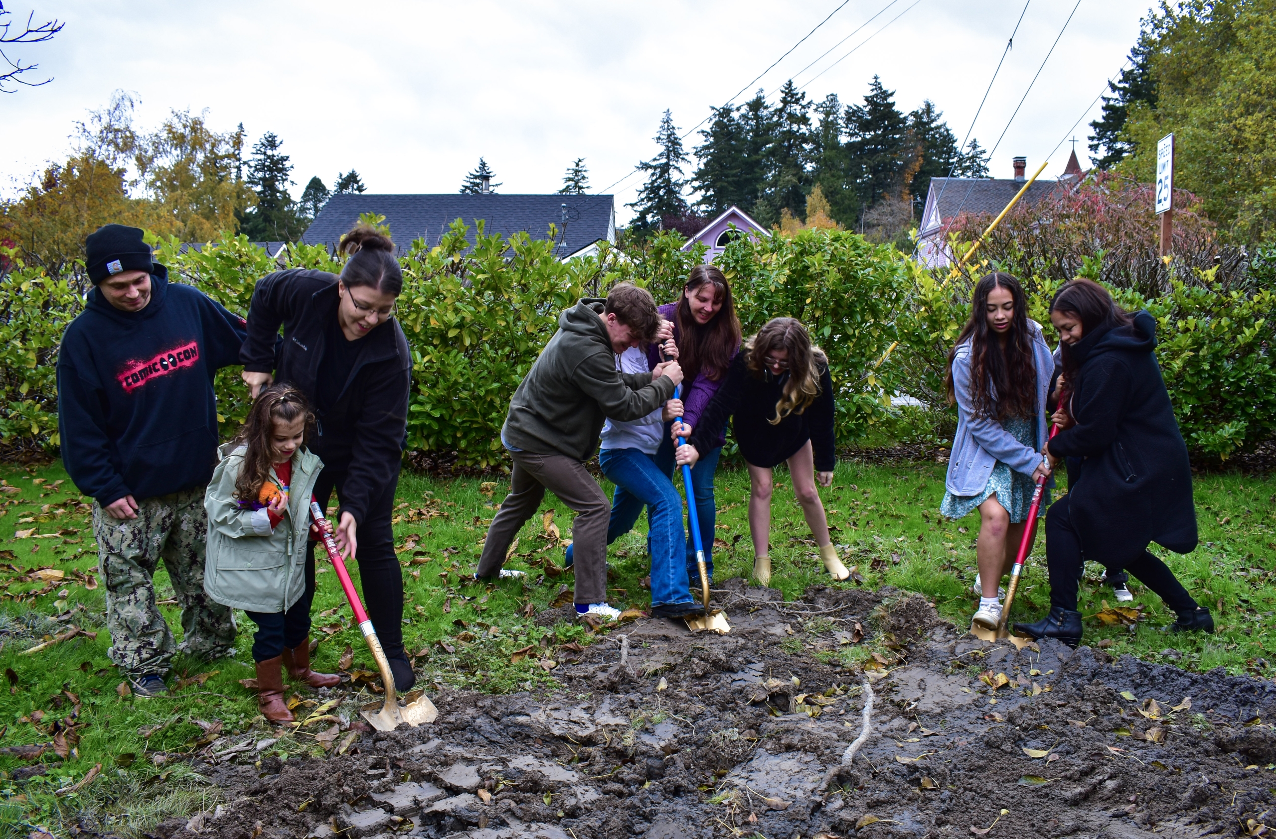 Three families digging into the ground with symbolic golden shovels at Skagit Habitat for Humanity's Groundbreaking Ceremony