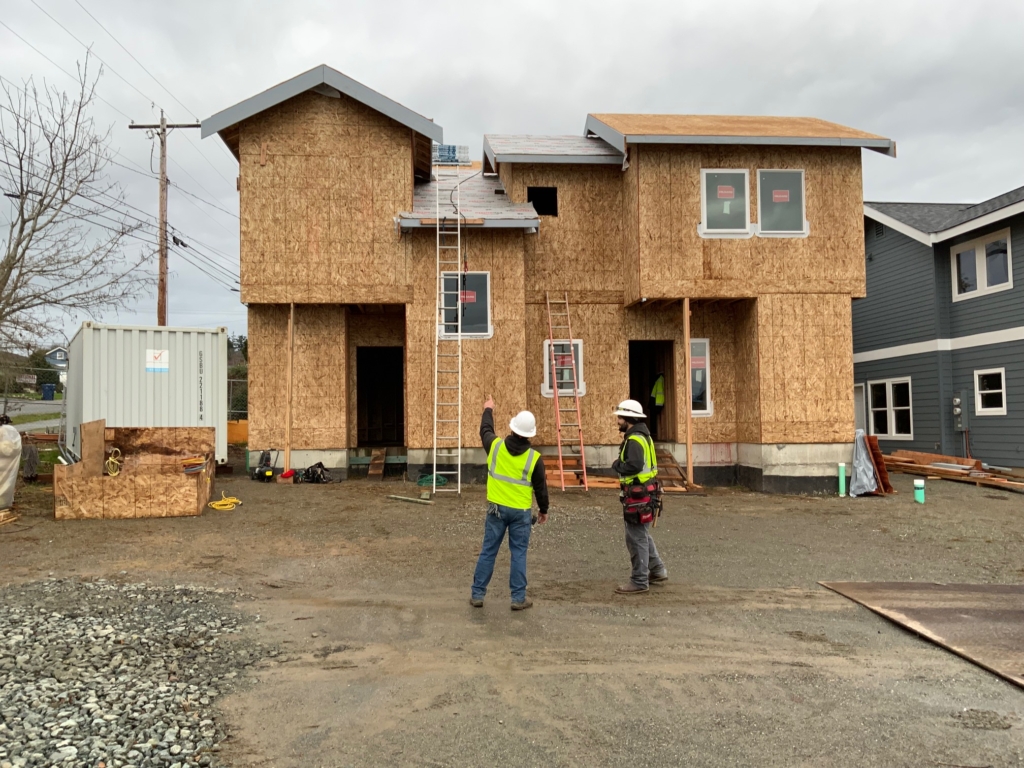 two construction workers in yellow vests pointing at a construction project