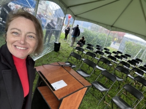 April Patterson smiling in front of a podium and chairs for Skagit Habitat for Humanity's Groundbreaking Ceremony in La Conner.