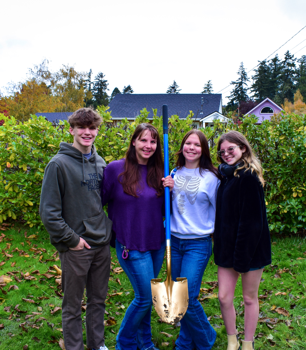 Homebuyer Program family, Tarra and her children standing on the construction site at Skagit habitat's groundbreaking ceremony with a golden shovel.