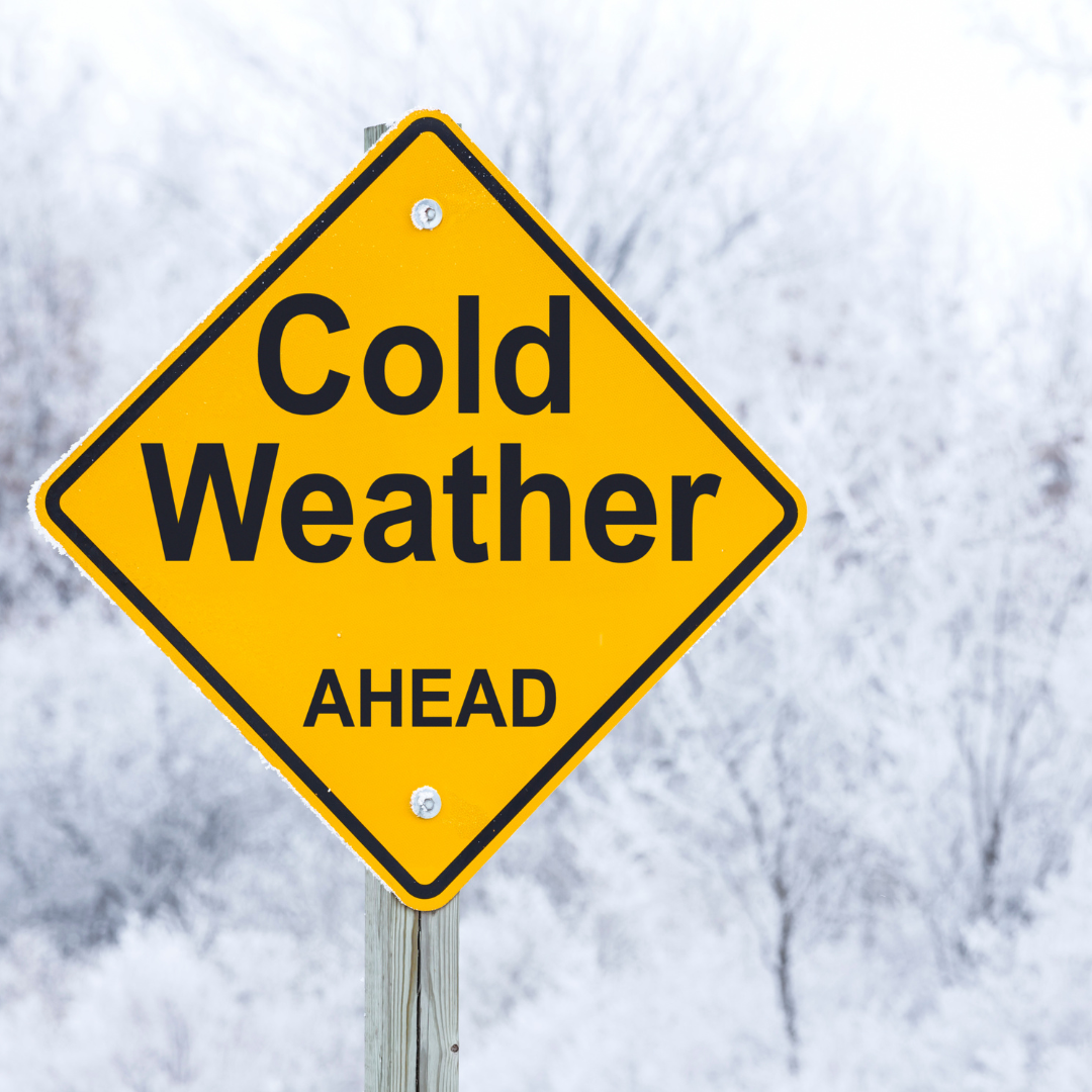 yellow cold weather ahead road sign with a snowy outdoor background