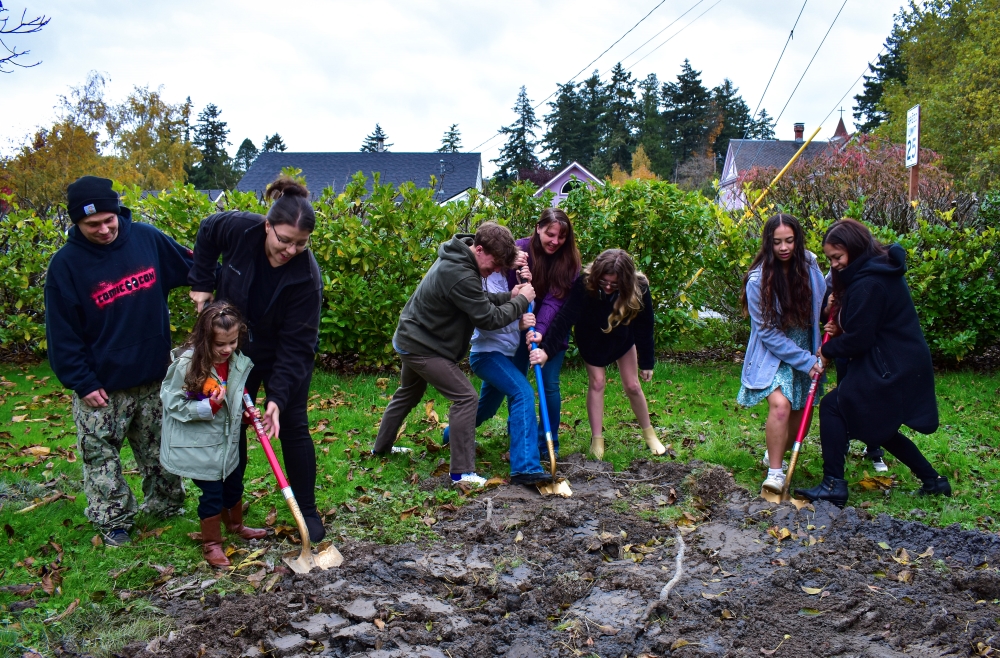 Three families digging their golden shovels, marking breaking ground for their future permanently affordable homes.