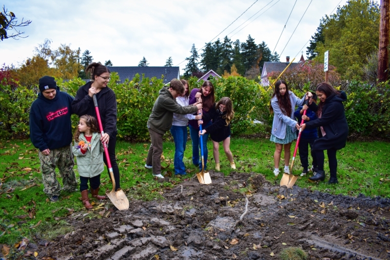 Three families digging their golden shovels, marking breaking ground for their future permanently affordable homes.